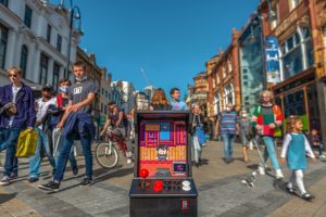 A brightly coloured arcade game with a joystick in the middle of a busy street