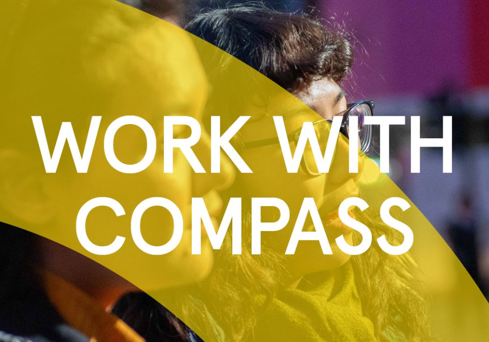 Close up of the faces of two people, both white who are looking to the right. They are audience members of a Compass Festival Event. There is a Yellow arch graphic that goes across the image, what text that says "work with compass" is written across the whole image.