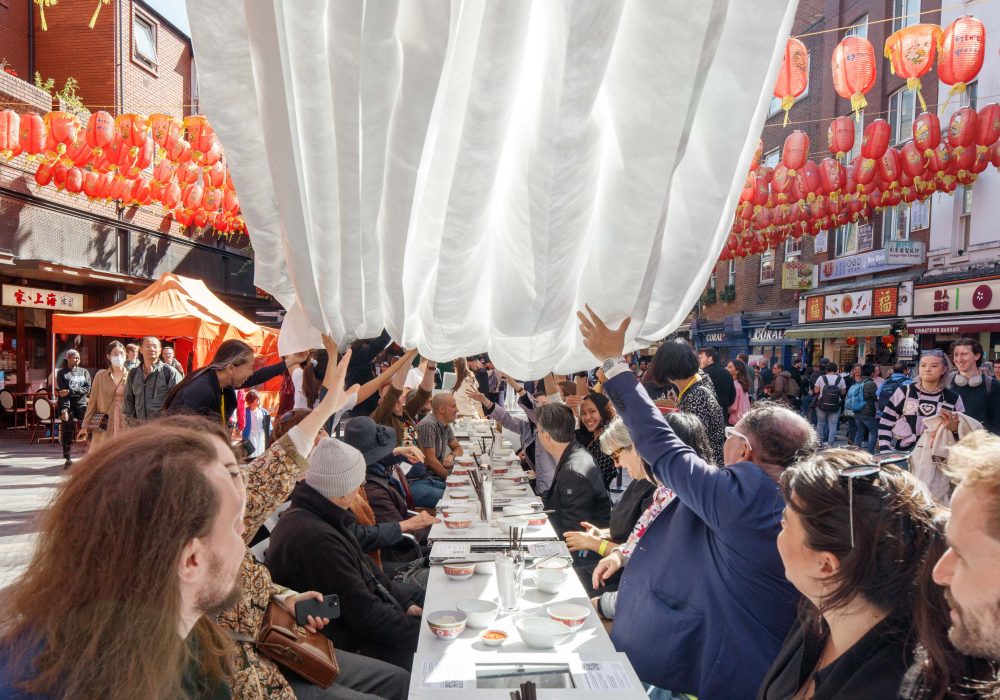 People sat around a table outside sharing a meal in Chinatown in London