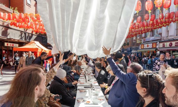 People sat around a table outside sharing a meal in Chinatown in London