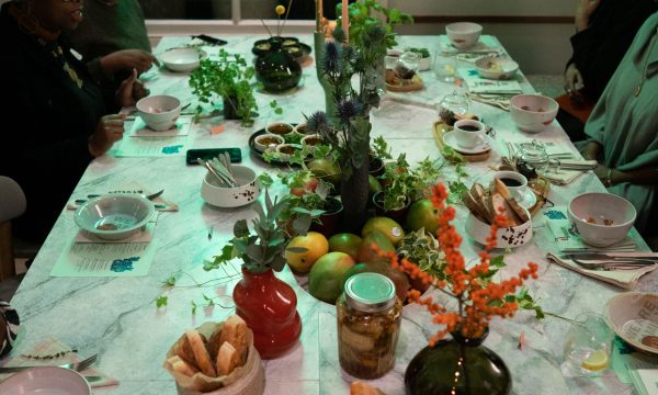 A table of food, plates and people around the edge, with green lighting